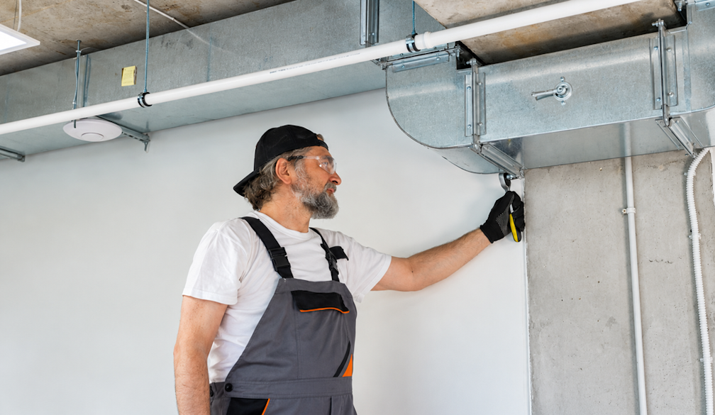 HVAC Worker Adjusting Ceiling Ductwork