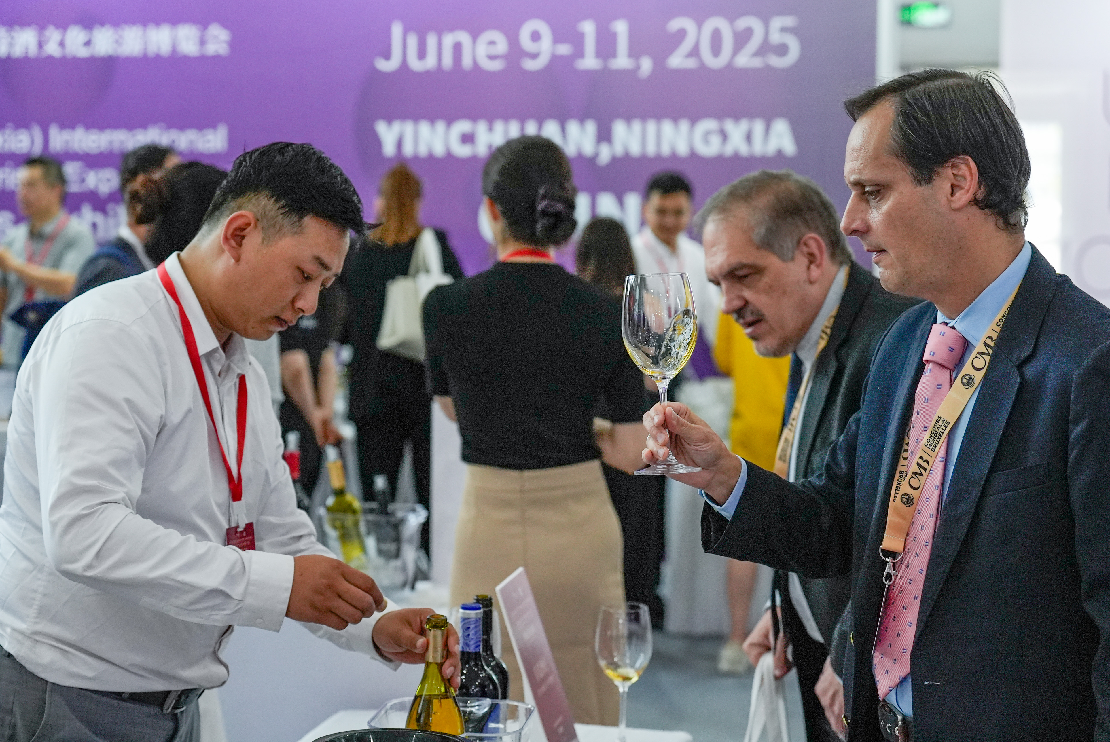 A visitor (1st R) tastes wine at the Global Wineries Exhibition during the Fifth China (Ningxia) International Wine Culture and Tourism Expo in Yinchuan, northwest China